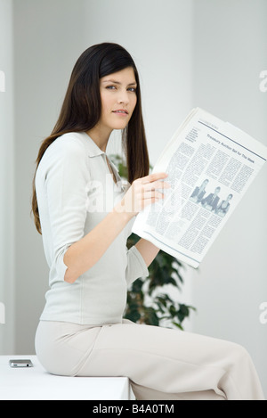 Business-Frau, sitzen, halten Sie Zeitung, Blick in die Kamera Stockfoto