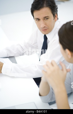 Professionelle Mann sitzt am Schreibtisch, im Gespräch mit Kollegin, erhöhte Ansicht Stockfoto