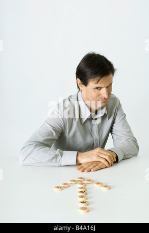 Mann sitzt vor gemacht von Mahjong Fliesen, Pfeil nach unten Stockfoto