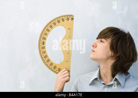 Junger Mann hält Winkelmesser, Profil Stockfoto