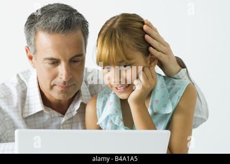 Vater und Tochter Blick auf Laptop-Computer zusammen, Mannes hand aufs Mädchenkopf Stockfoto