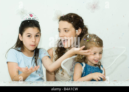 Mädchen werfen Konfetti, Mutter und Schwester beobachten Stockfoto