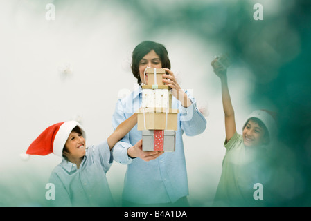 Junger Mann und jungen Stapeln Weihnachtsgeschenke, lächelnd, jungen Santa Hüte tragen Stockfoto