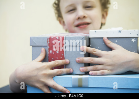 Kleiner Junge hält Arm voller Geschenke, Lächeln Stockfoto