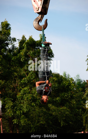 Jadugar Akash angekettet voll hängen in der Luft mit Hilfe eines Krans im Vorspiel zur Feuerleiter Show in Trivandrum, Kerala, Stockfoto