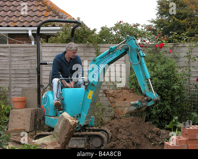 Baumeister Bauarbeiter mit einem Dowling Kaninchen Minibagger Bagger Boden vor arbeiten an einer Erweiterung zu entfernen Stockfoto