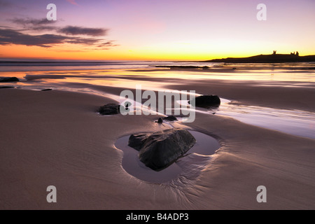 Sonnenaufgang am Embleton Bay mit Dunstanburgh Castle Silhouette am Horizont Northumberland Stockfoto