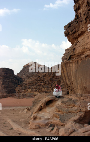 Arabische Mann sitzt auf dem Felsen, Wadi Rum, Jordanien Stockfoto