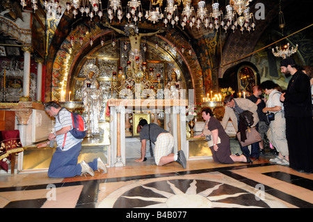 Christliche Pilger kniend und betend vor einem Kreuz im Inneren der Kirche des Heiligen Grabes in Jerusalem, Israel Stockfoto