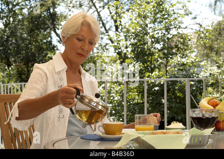 Reife Frau sitzen auf dem Balkon frühstücken Stockfoto