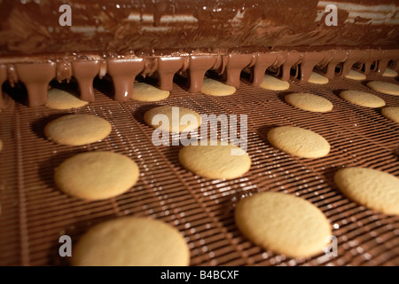 Schokolade tropft auf frisch zubereiteten "Momente" Kekse auf Förderband der Delacre Keks Produktion Fabrik in Lambermont Stockfoto