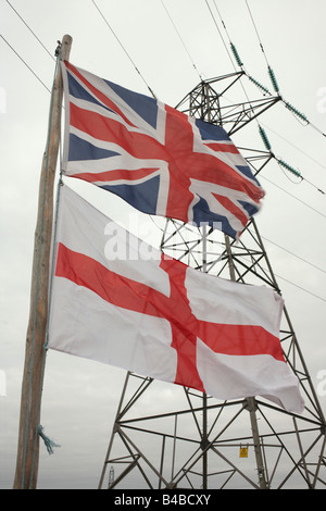 Ein Union Jack-Flagge fliegt unter den englischen Kreuz des Heiligen Georg auf eine Fahnenstange unter einem Strommast in einem Garten von Somerset Stockfoto