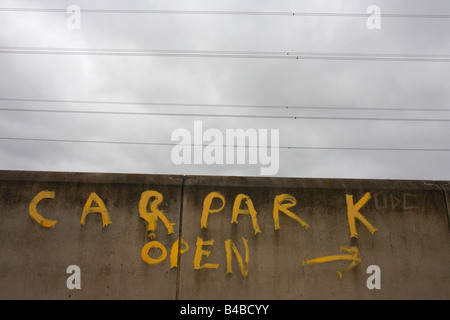 Unter Stromleitungen ist die gelbe Schrift an der Wand, lesen "Parkplatz offen" auf Industriebrachen in East London gemalt. Stockfoto