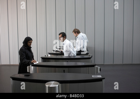 Eine verschleierte muslimische Dame geht Männer Sicherheitsbarrieren von einer Wirtschaftsprüfungsgesellschaft Europazentrale Stockfoto