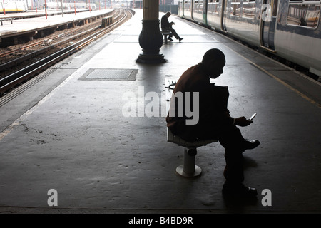 Silhouette Pendler und warten auf den Bänken ankommenden Zug auf überdachten Plattform an der Hauptstrecke Station London Bridge Stockfoto