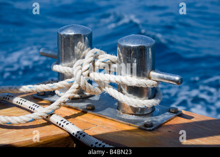 Knoten Sie auf einem Poller eines Bootes. Blaue Meer im Hintergrund. Stockfoto