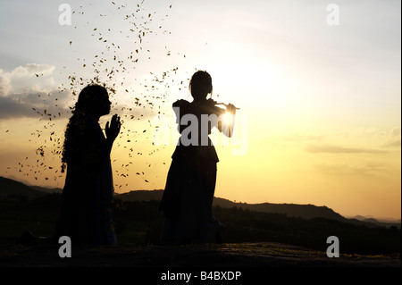 Zwei indische Schwestern Durchführung einer hinduistischen frommen Tanzes auf einem Felsen bei Sonnenuntergang Silhouette. Andhra Pradesh, Indien Stockfoto