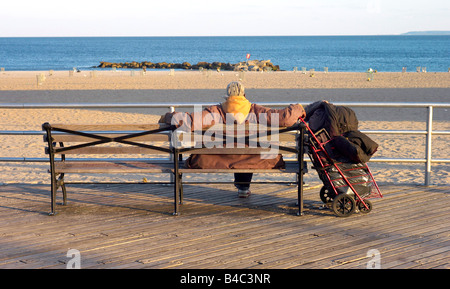 Obdachloser auf Bank Blick auf das Meer auf Conely Island New York USA Stockfoto