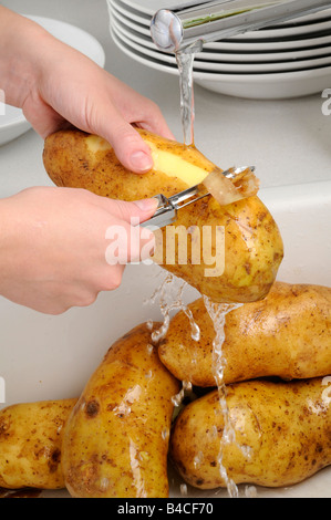 FRAU SCHÄLEN KARTOFFELN Stockfoto