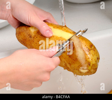 FRAU SCHÄLEN KARTOFFELN Stockfoto