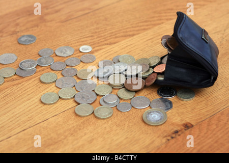 Münzen aus der Handtasche verschütten Stockfoto