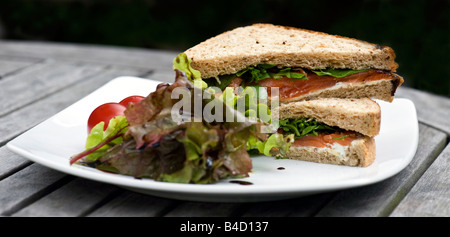 Räucherlachs, Kresse und Frischkäse Sandwich mit Tomaten, gemischte Blätter und Balsamico, serviert auf einem weißen Teller. Stockfoto