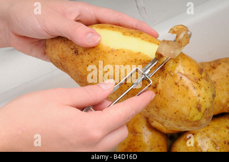 FRAU SCHÄLEN KARTOFFELN Stockfoto