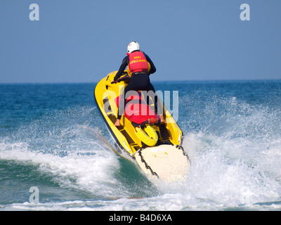 RNLI Rettungsschwimmer auf eine Rettung Jetski durch eine Welle Stockfoto