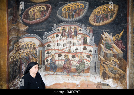 Alte Frau durch religiöse Malerei an der Wand außerhalb der Kirche im 14. Jahrhundert befestigten Kloster. Cozia Transylvania Rumänien Europa Stockfoto