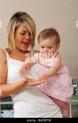 junge Mutter und ihre kleine Tochter lachten und spielten zusammen. Stockfoto