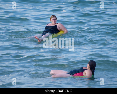 Zwei übergewichtige Frauen auf Gummiringe im Meer Stockfoto