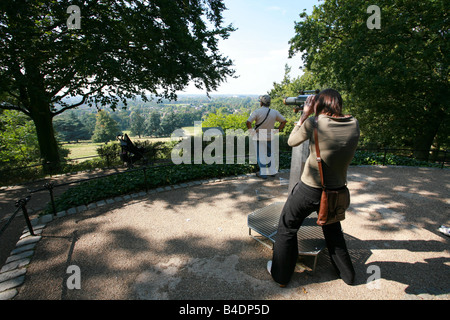 Junge weibliche Touristen Besucher Richmond Park nutzt kostenlose Teleskop Thames Valley Surrey Landschaft aus St. Henrys Mount anzeigen Stockfoto