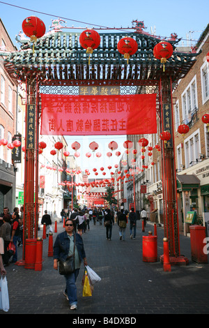 Touristen gehen unter rote Haupttor Eingang zu China Town im Londoner West End England UK Stockfoto