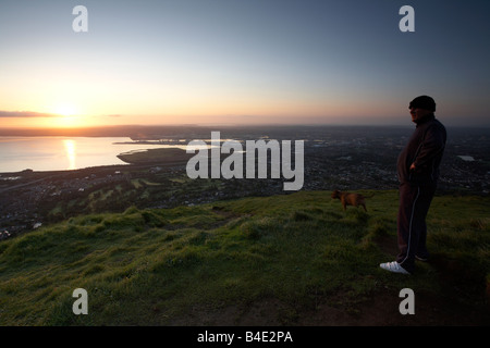 Mann mit seinem Hund stehend genießen Sie den Blick von oben von Cave Hill mit Blick auf Belfast Belfast Nordirland Vereinigtes Königreich Stockfoto