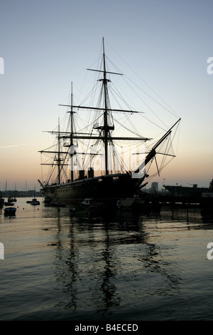 Stadt von Portsmouth, England. Silhouette Abenddämmerung Blick auf HMS Warrior bei Portsmouth Historic Dockyard festgemacht. Stockfoto