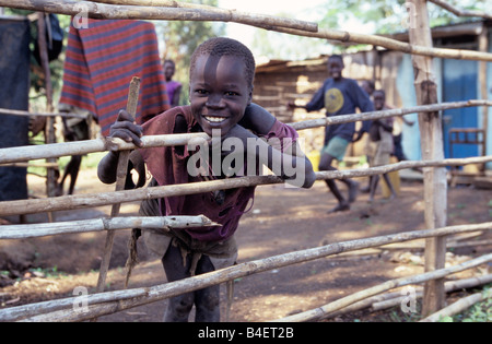 Eine ethnische Karamojong Junge lehnte sich gegen Zaun, Porträt, Karamoja, Uganda, Afrika Stockfoto