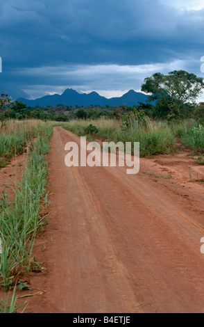 Landschaft mit ländlichen Schotterstraße und Sturmwolken über die Berge in der Ferne, Uganda, Afrika Stockfoto
