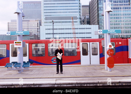 Mann mit Zeitung warten auf Zug, Poplar Station, London, England, Großbritannien Stockfoto