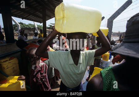 Frau, die Jerry kann auf Kopf, unter anderem das Sammeln von Wasser in Displaced Persons Camp, Angola Stockfoto