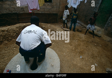 Eine humanitäre Arbeiter aus NGO "Ziel" zeigt eine neu gebaute Toilette in einem Lager für Vertriebene in Angola. Stockfoto