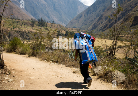 Ein Portier trägt eine schwere Last entlang des Inka-Trail oder Camino Inka in den hohen Anden Perus Stockfoto