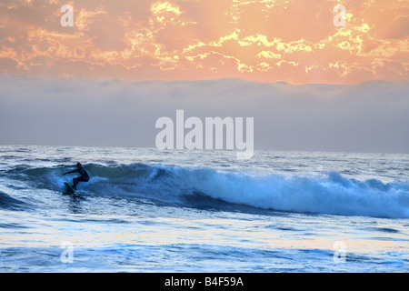 Ein Surfer, der die Wellen Südkaliforniens unter einem wunderschönen Sonnenuntergang reitet. Stockfoto