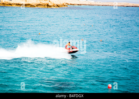 Eine Rettung Jet Ski patrouillieren in den Gewässern vor Nissi Beach, Zypern, mit Schwimmer im Wasser Stockfoto