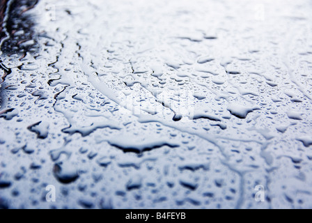Regen Sie Wasser Tropfen Muster auf der Motorhaube des glänzenden dunklen blaues Auto Stockfoto