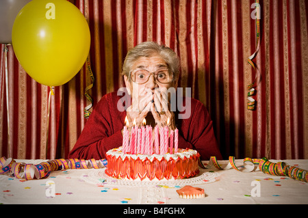 Erstaunt alte Großmutter verloren ihr Zahnersatz, während sie versuchen, Ausblasen der Kerzen auf dem Kuchen zum Geburtstag Stockfoto