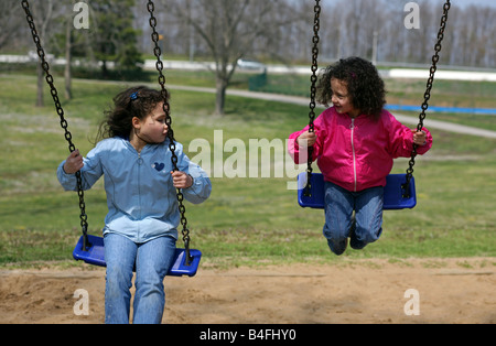 Zwei hübsche Mädchen, Schwestern, schwingen Sie gemeinsam in einem lokalen Park an einem sonnigen Frühlingstag, ihre langen braunen Haare hinter! Stockfoto