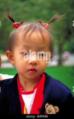 Eine hübsche junge Chinesin mit ihr Haar in Zöpfen geniesst den Tag im Stanley Park, Vancouver British Columbia, Kanada. Stockfoto