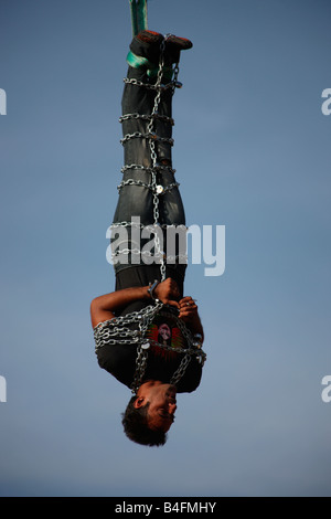 Jadugar Akash angekettet voll hängen in der Luft mit Hilfe eines Krans im Vorspiel zur Feuerleiter Show in Trivandrum, Kerala, Stockfoto