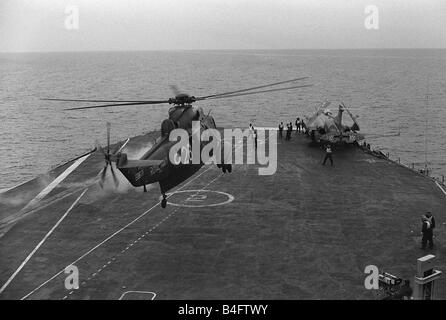 Ein Royal Navy Westland Sea King schwebt über dem Deck als eine Buccaneer mit gefalteten Flügeln an Bord der Aircraft Carrier HMS Ark Royal 1971 sitzt Stockfoto