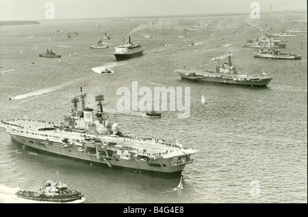 Die Cunard-Liner QEII Kreuzfahrten durch die Flotte von Schiffen der Royal Navy versammeln sich am Spithead für die Königinnen Silberjubiläum Überprüfung im Vordergrund der Flugzeugträger HMS Ark Royal und HMS Hermes Juni 1977 Stockfoto